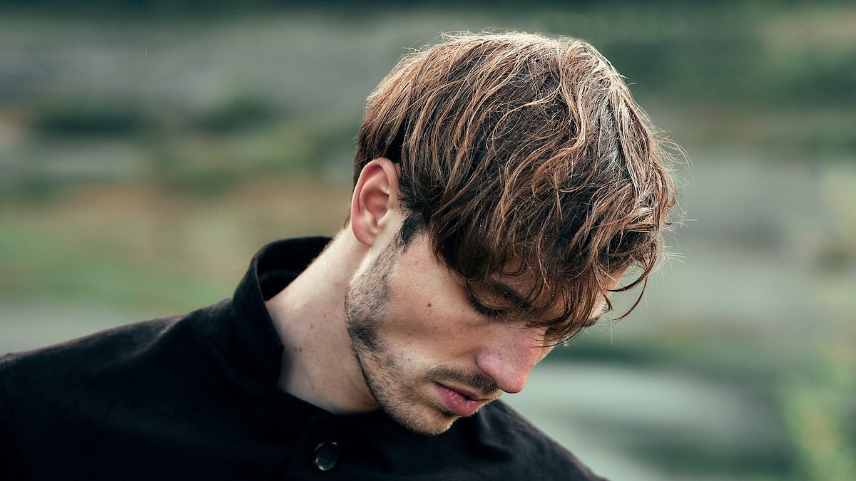 Person with a contemplative expression, wearing a dark buttoned shirt. The setting or event is not specified
