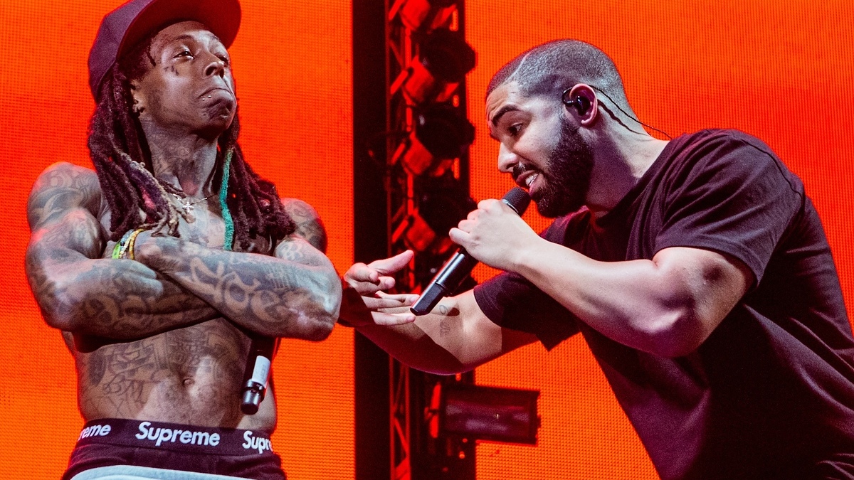 Two artists perform on stage, one in a graphic tee and the other in a casual shirt, both engaging with the audience