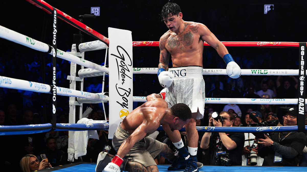 Two boxers in a ring, one ducking a punch, the other throwing it, surrounded by spectators