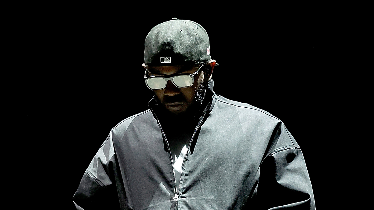 Man in sunglasses and cap, wearing a sporty jacket, on a stage