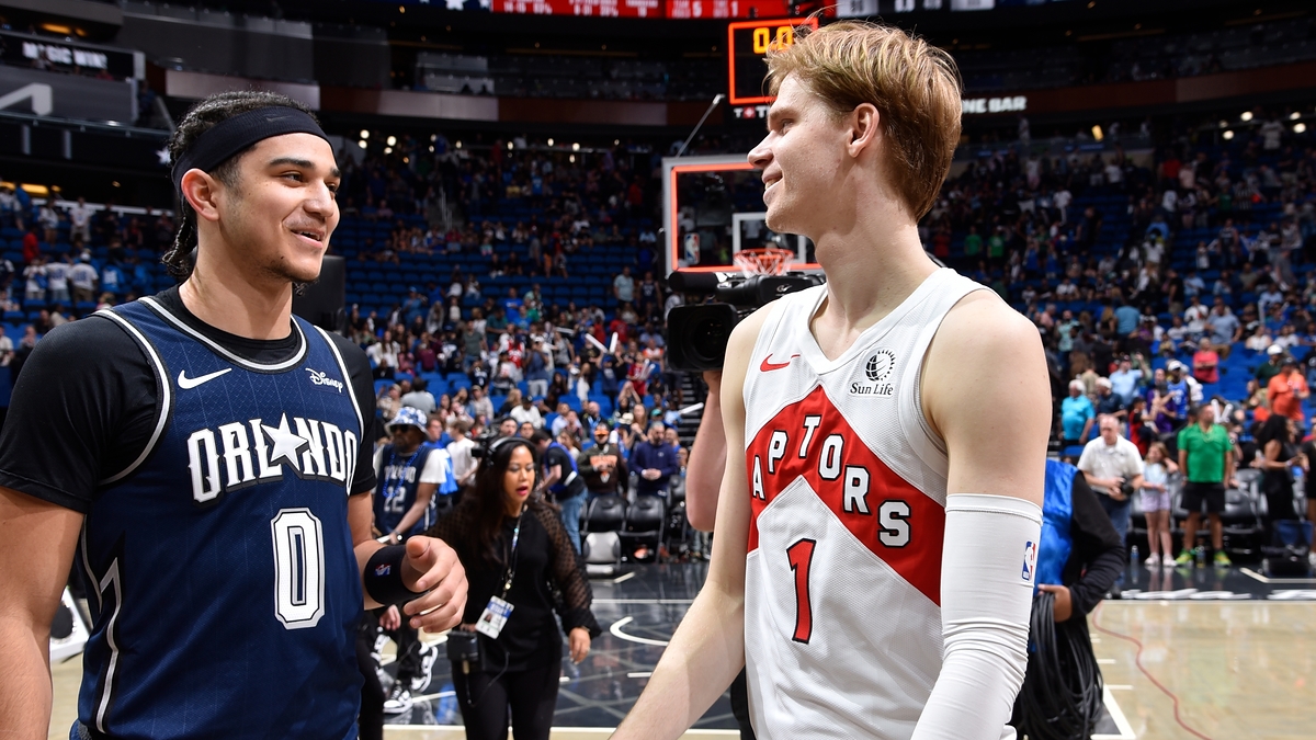 Two basketball players from opposing teams are having a friendly chat on the court post-game