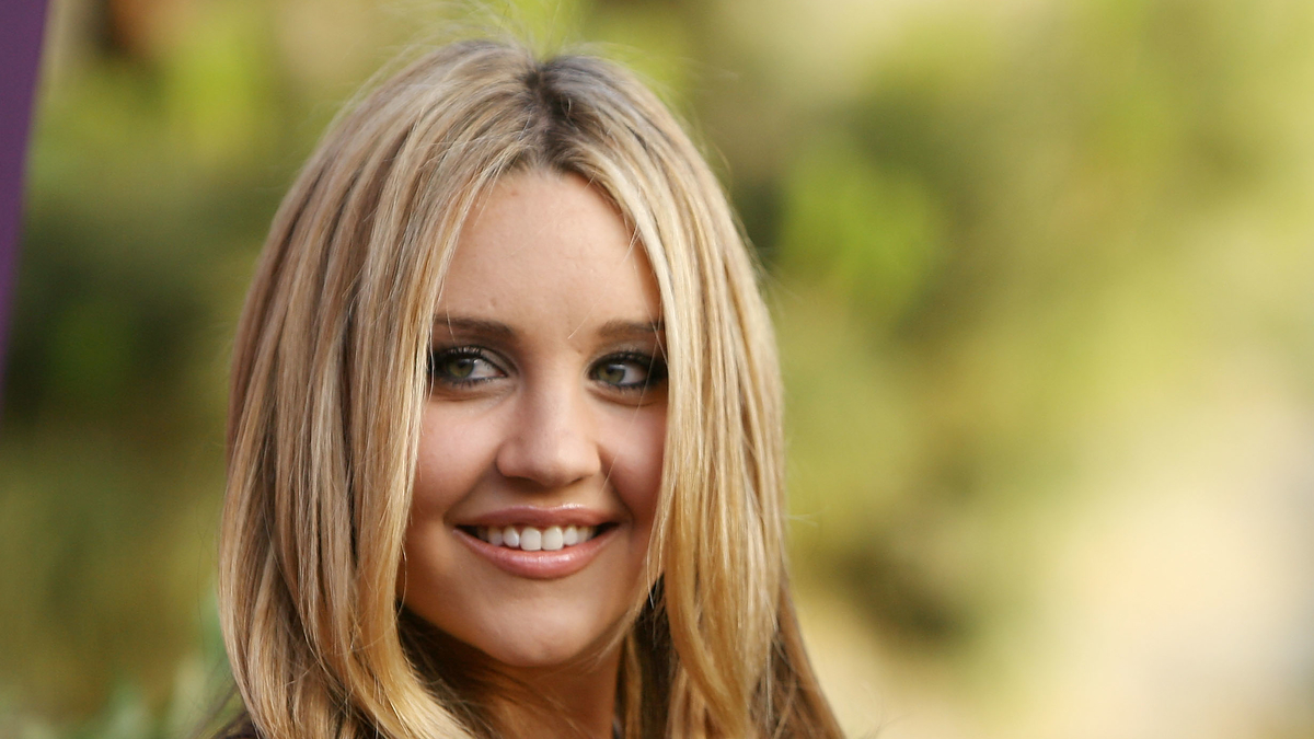 Woman with blonde hair wearing a V-neck top, smiling outdoors