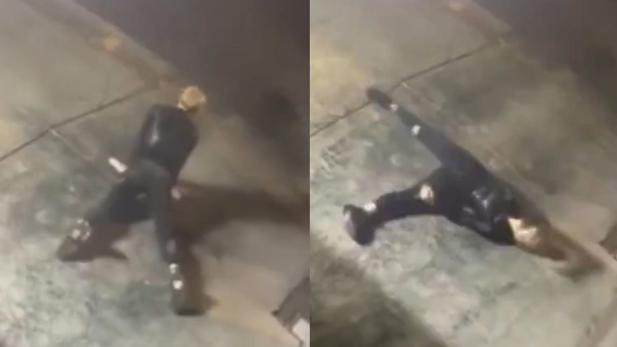 Person in dark suit and boots slips and falls on pavement