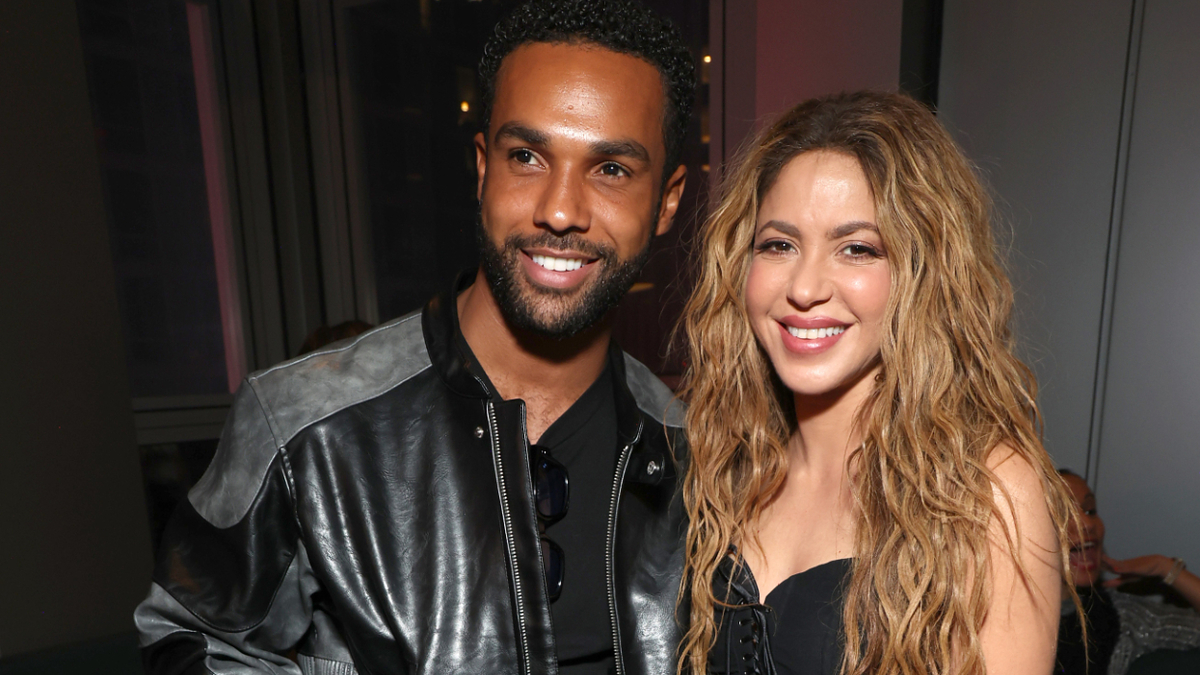 Two individuals smiling at an event, one with a leather jacket, the other with wavy hair