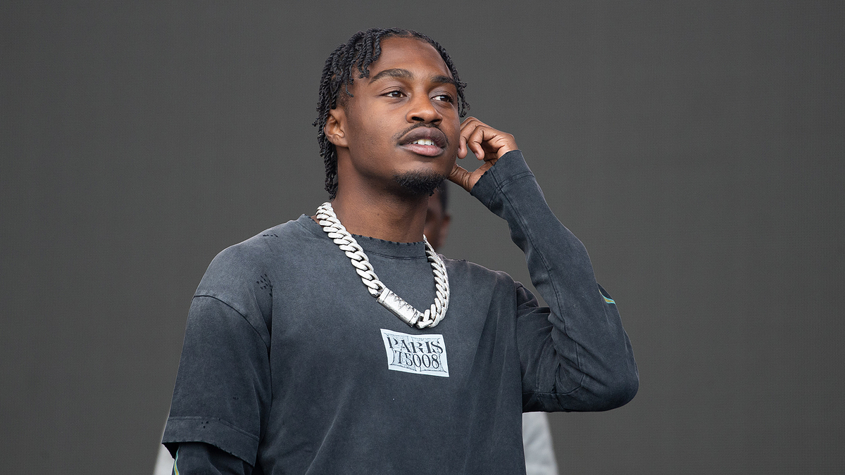 Person in a casual sweatshirt with chain necklace, holding a phone to their ear