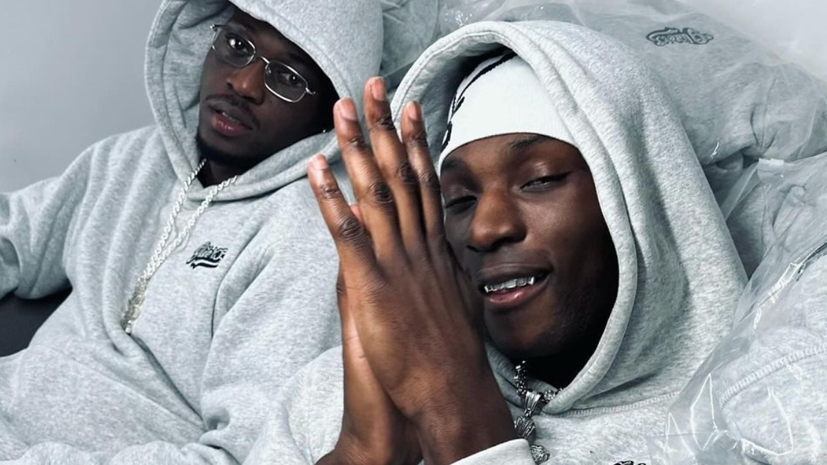 Two individuals in matching gray hoodies and jewelry posing for a photo