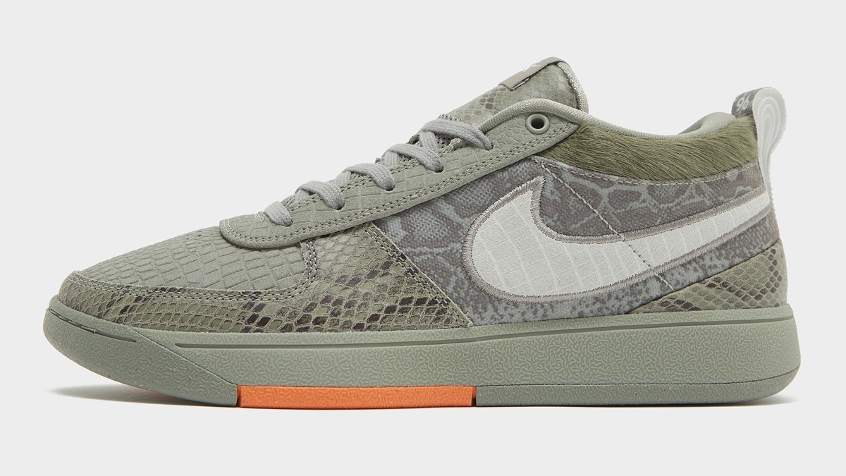 Nike sneaker with camo print and distinctive swoosh logo, hint of orange on outsole