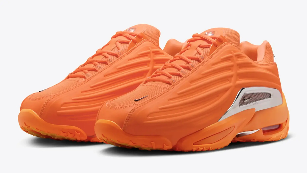 A pair of Nike Air Max 120 sneakers in a monochromatic bright orange design, showcased from a side angle