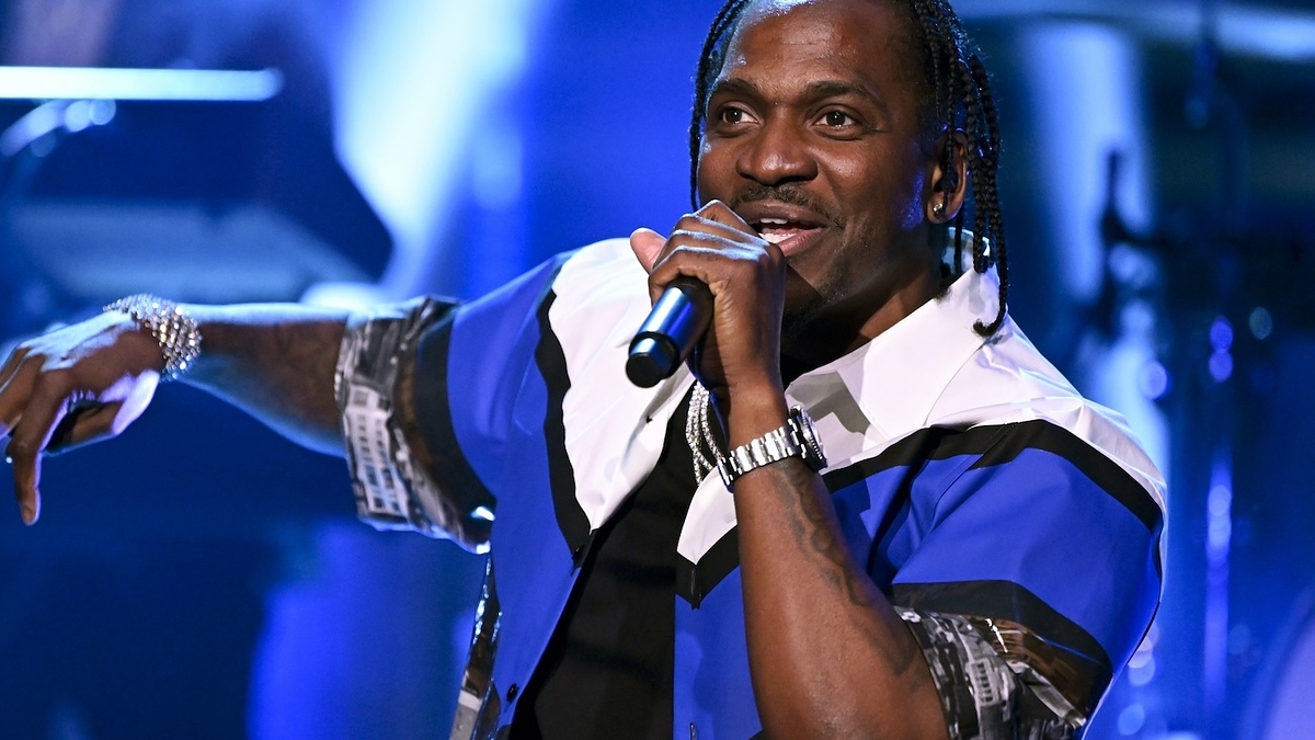 Musician in a striped shirt performing on stage with a microphone