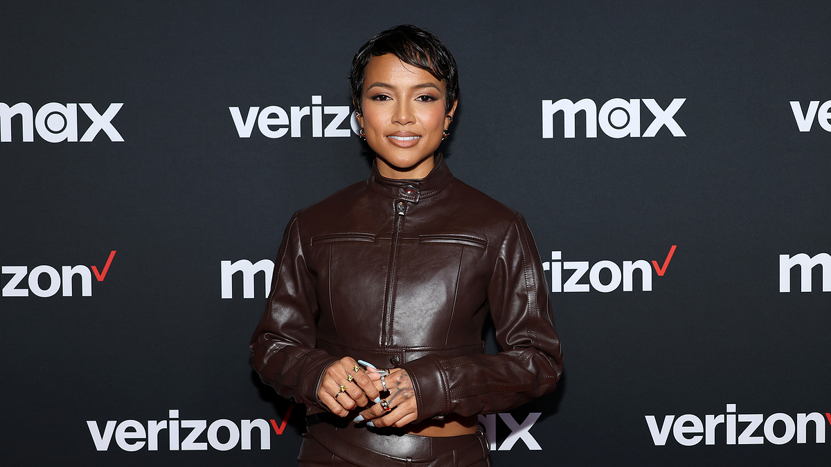 Woman in a fitted brown leather jacket posing for a photo