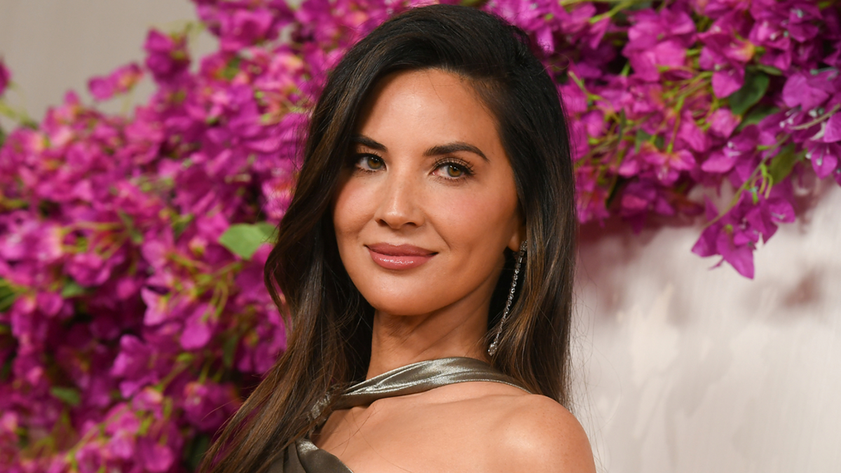 Woman in elegant silver gown posing with flowers in the background