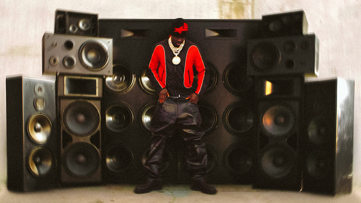 Person in red cap and jacket posing in front of large speakers with the phrase "This sh*t is a knocko" below