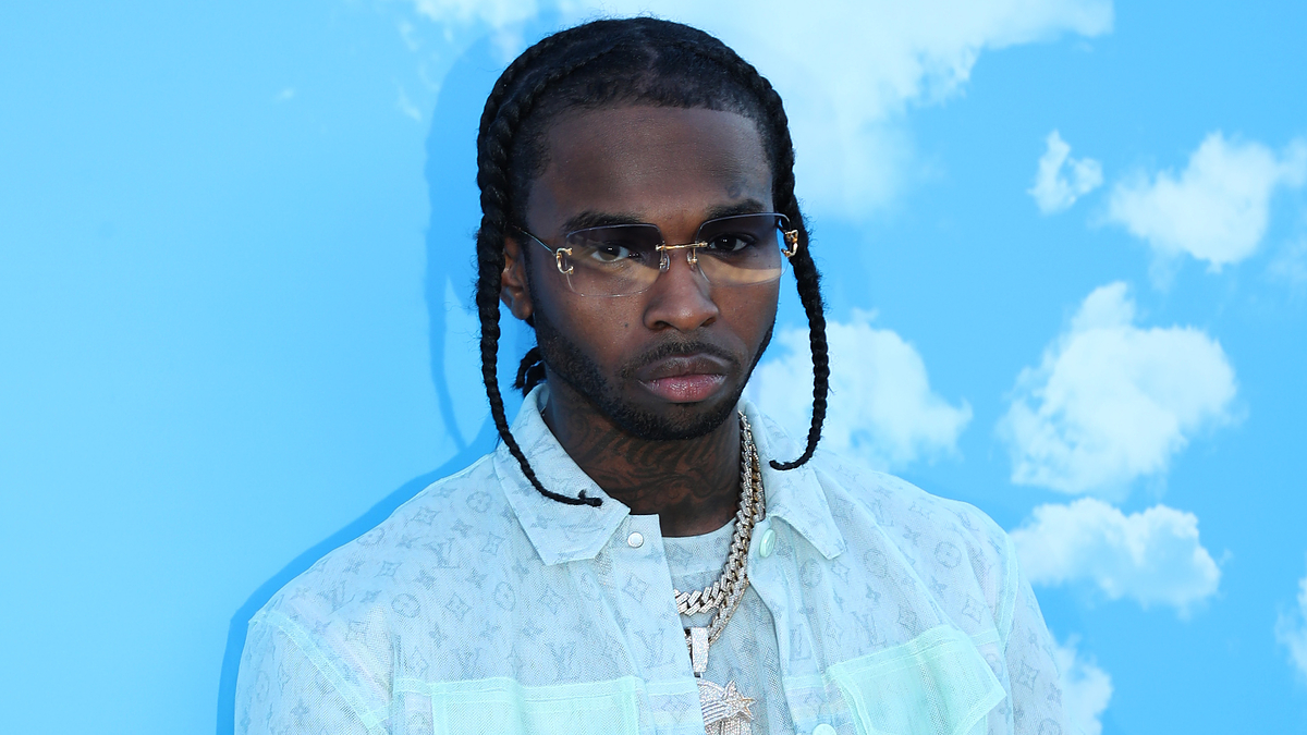 Pop artist in a light button-up shirt with braided hair and sunglasses