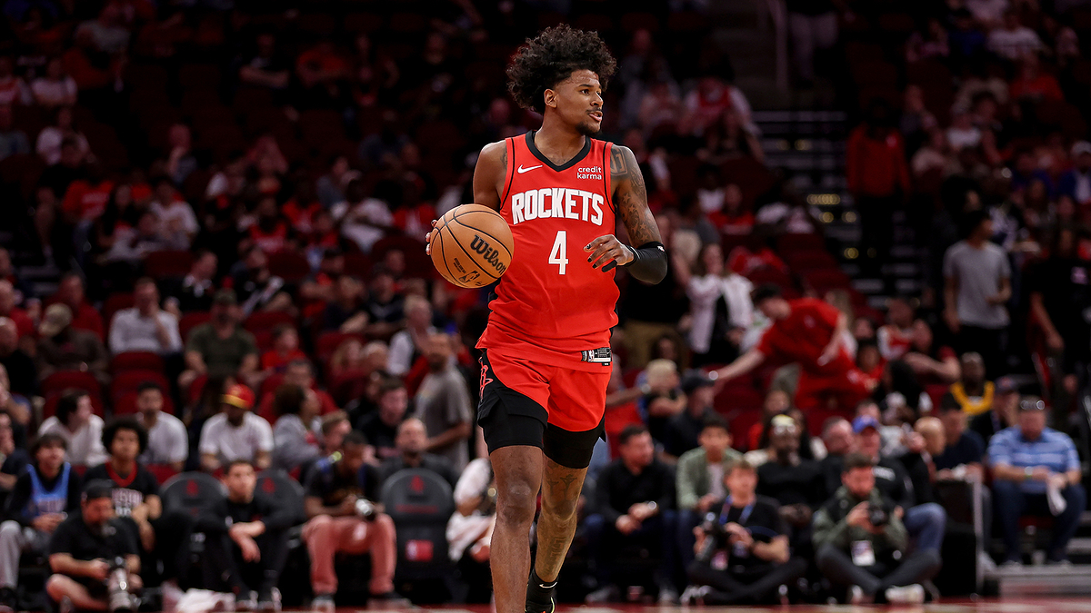 Basketball player in action wearing a Rockets uniform, number 4, dribbling in a game setting with audience in the background
