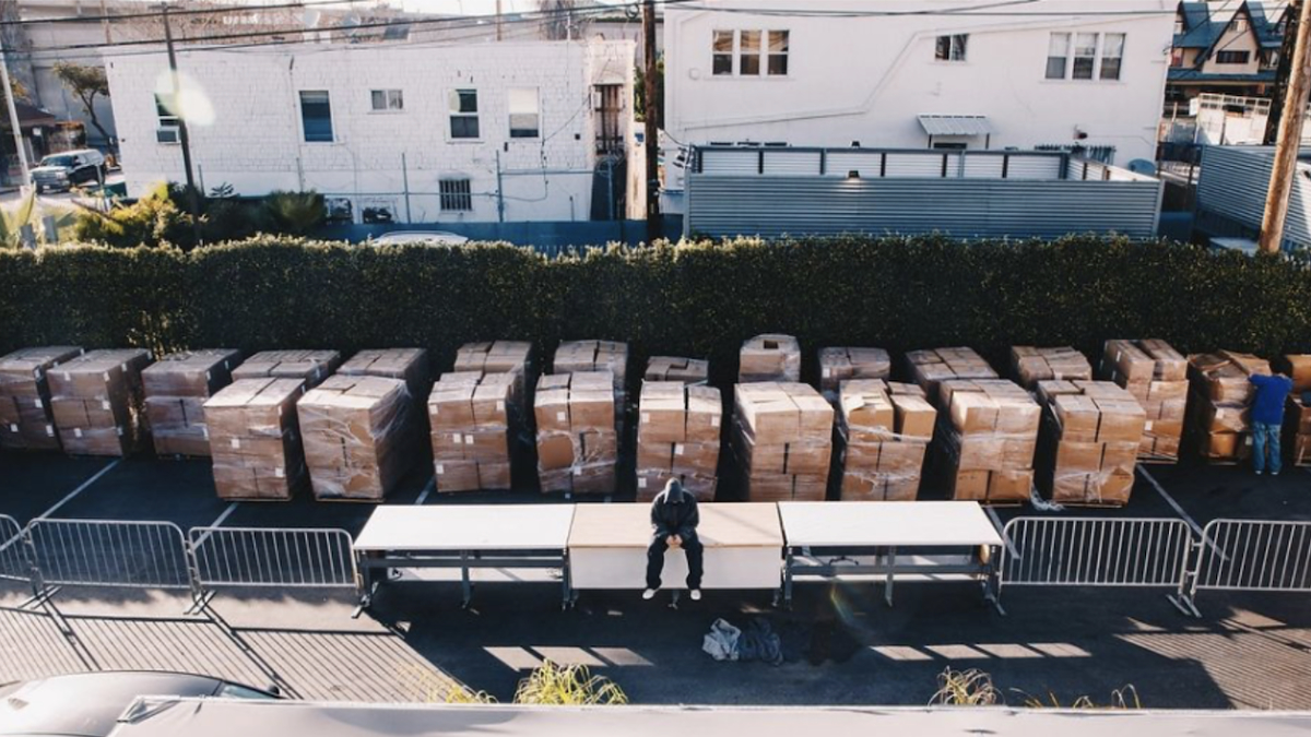 Person stands between rows of boxed supplies and a folding table in a logistics area