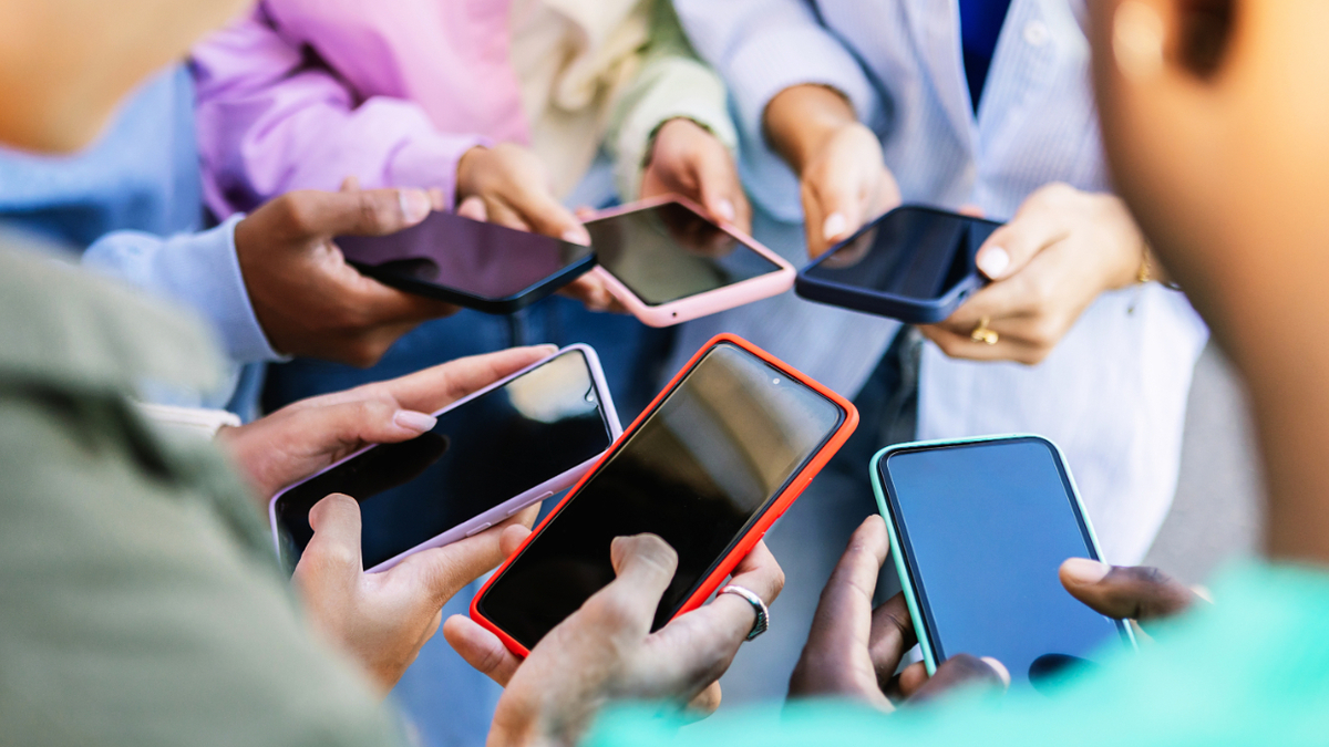 Group of people standing, each holding a smartphone, in a social gathering