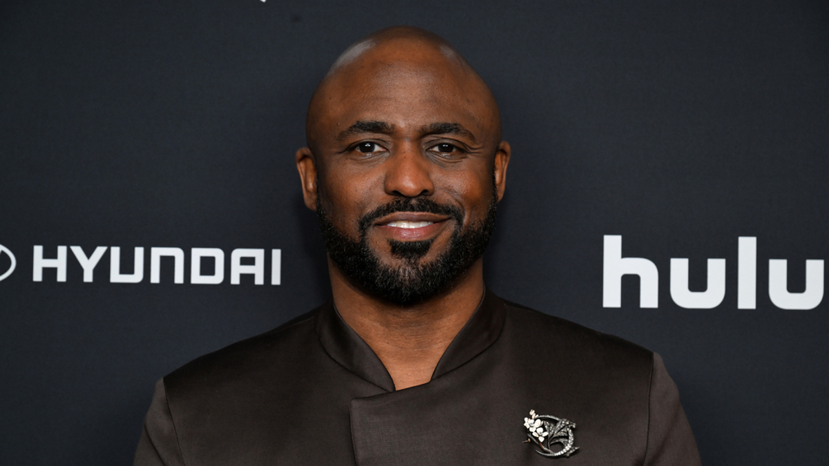 Man in a dark suit with a lapel pin posing for a photo at an event