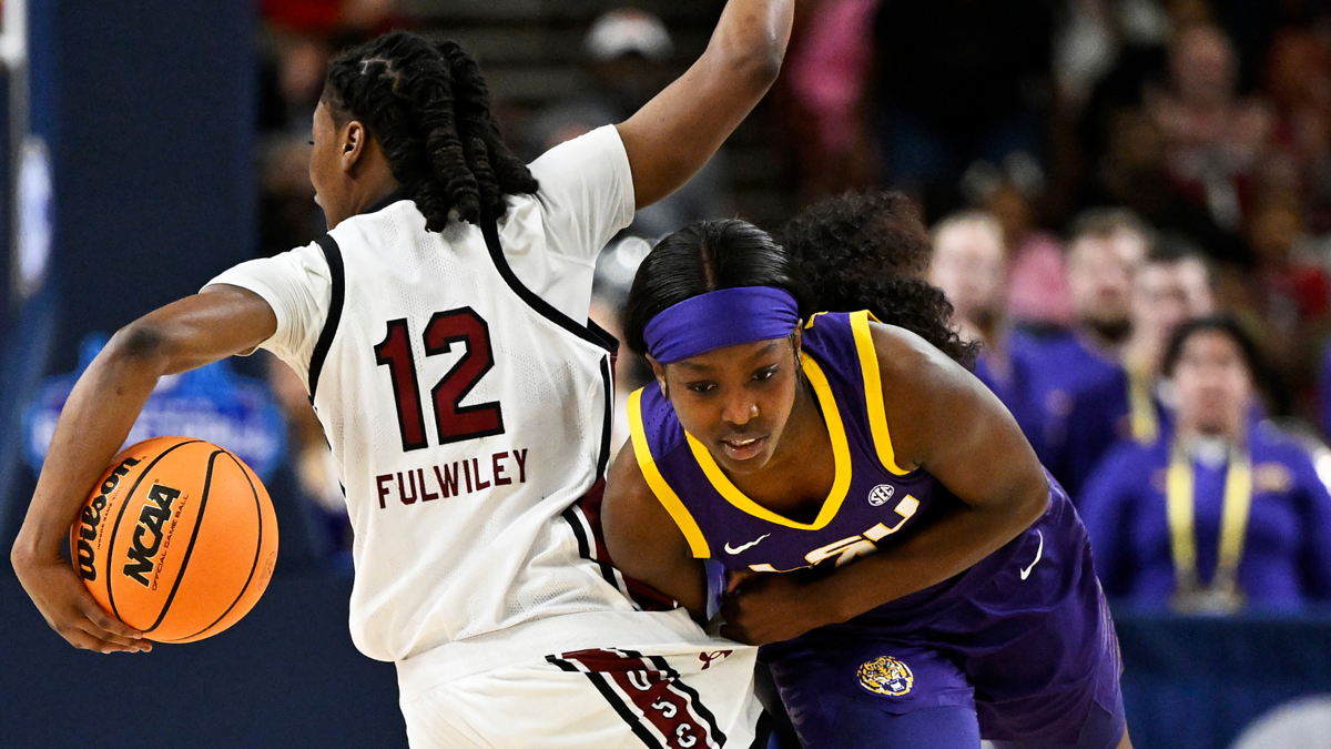 Two basketball players in action during a game with one defending the ball