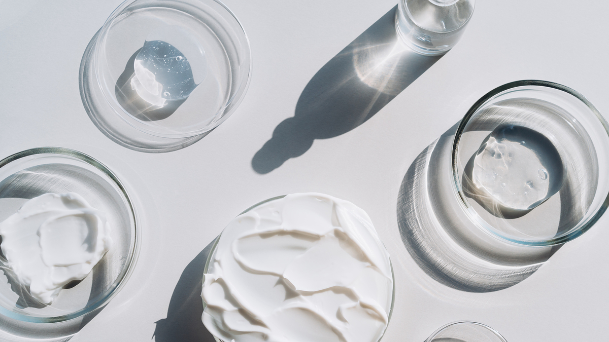 Assorted skincare products in clear containers with shadows on a surface