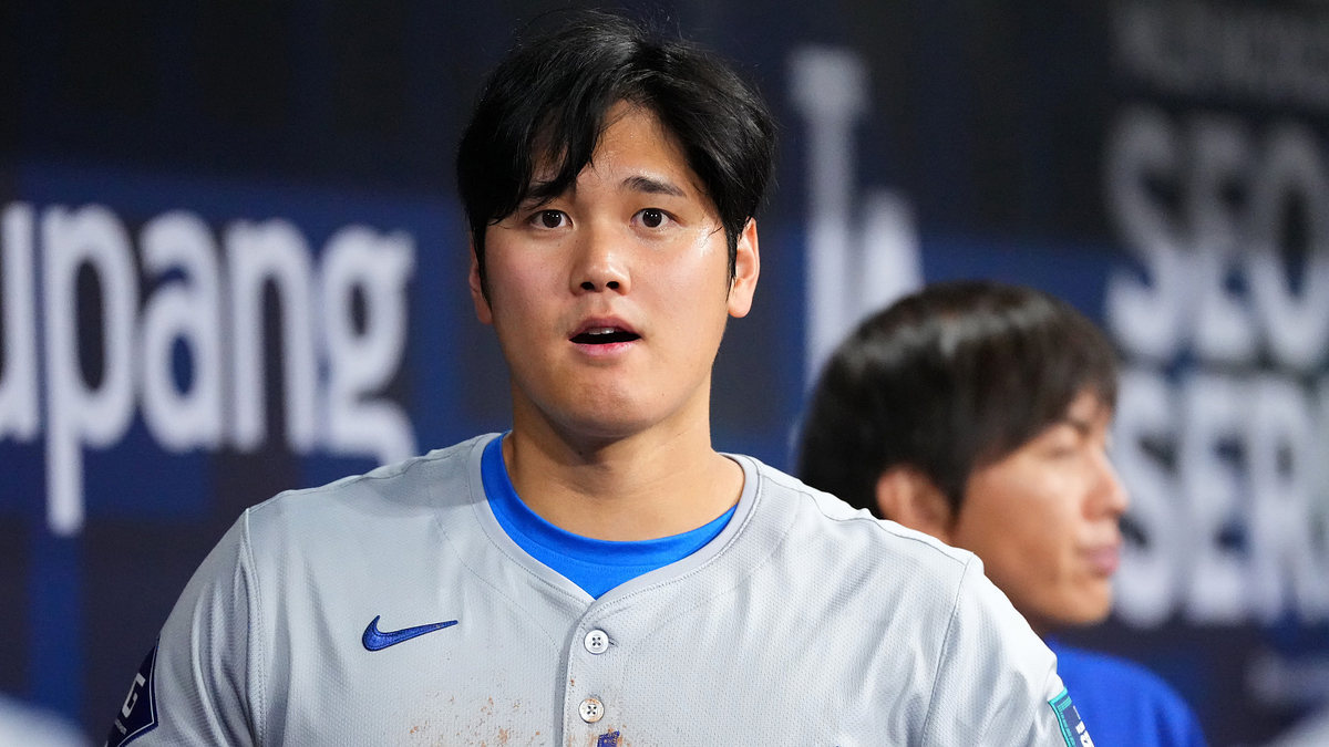 Baseball player in uniform with dirt stains, focused expression, and teammate in background