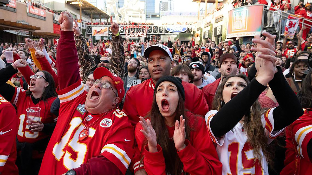 Excited fans in Kansas City Chiefs attire cheering at a game