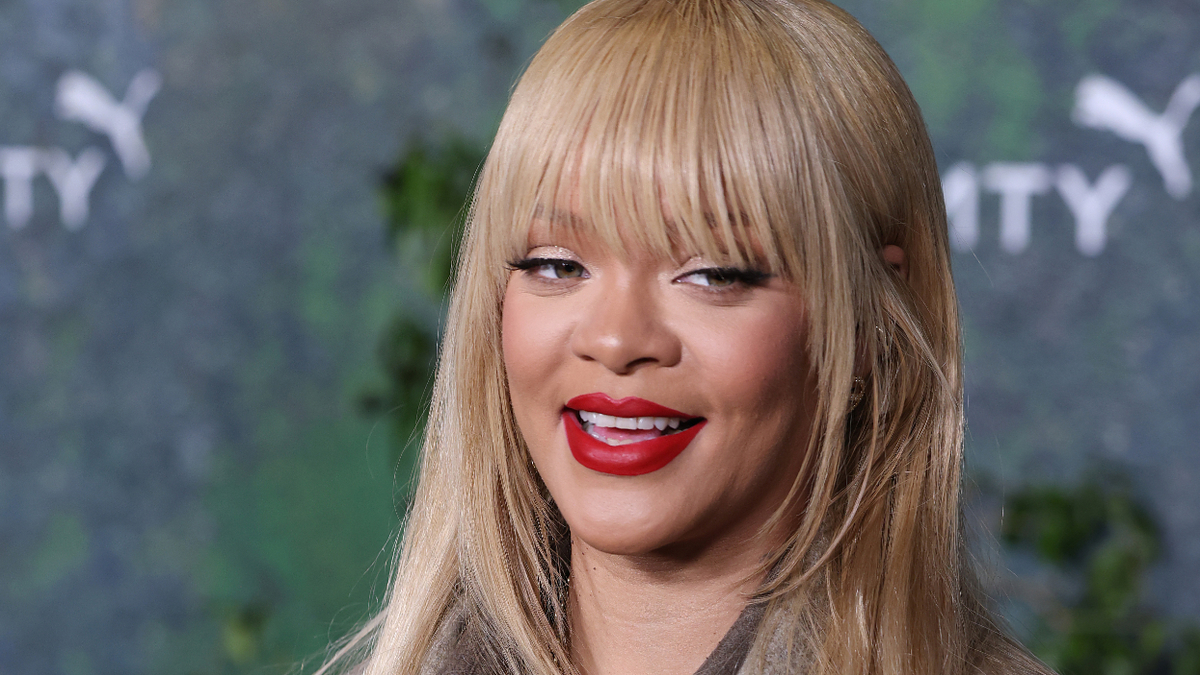 Woman with red lipstick and straight hair with bangs smiling