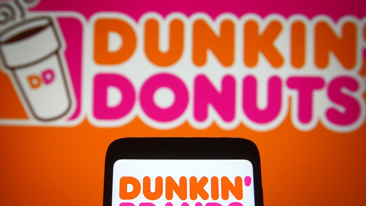 Dunkin' Donuts logo displayed on a screen, with a larger signage in the background