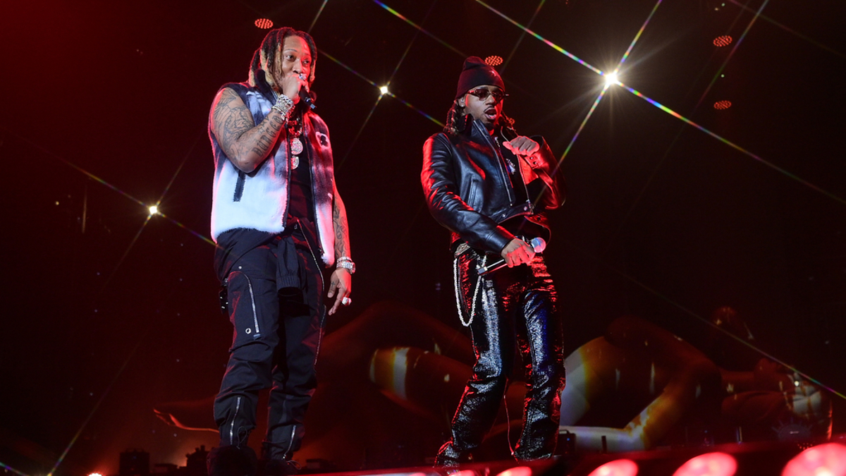 Two musicians performing on stage with microphones, surrounded by stage lighting