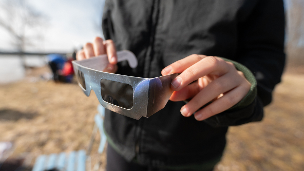 man holds eclipse glasses