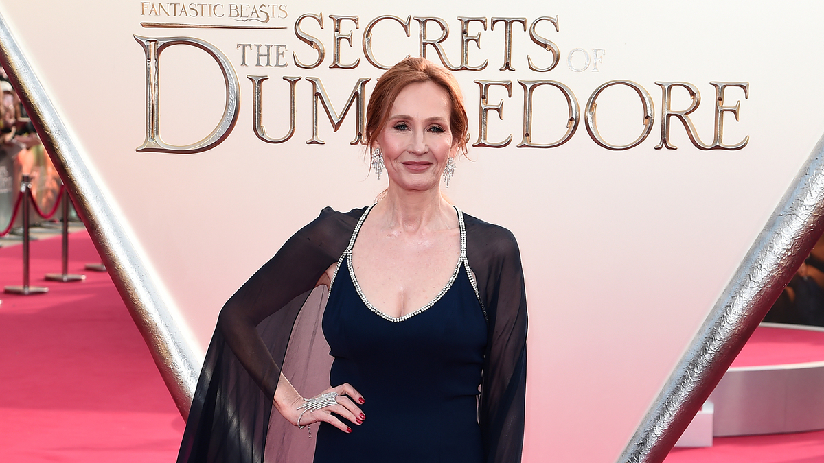 J.K. Rowling at the 'Secrets of Dumbledore' premiere, wearing a v-neck navy dress with sheer cape sleeves