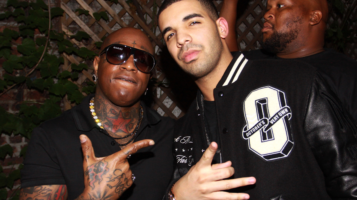 Two male musicians posing for a photo; one in a letterman jacket, the other in a black T-shirt with accessories