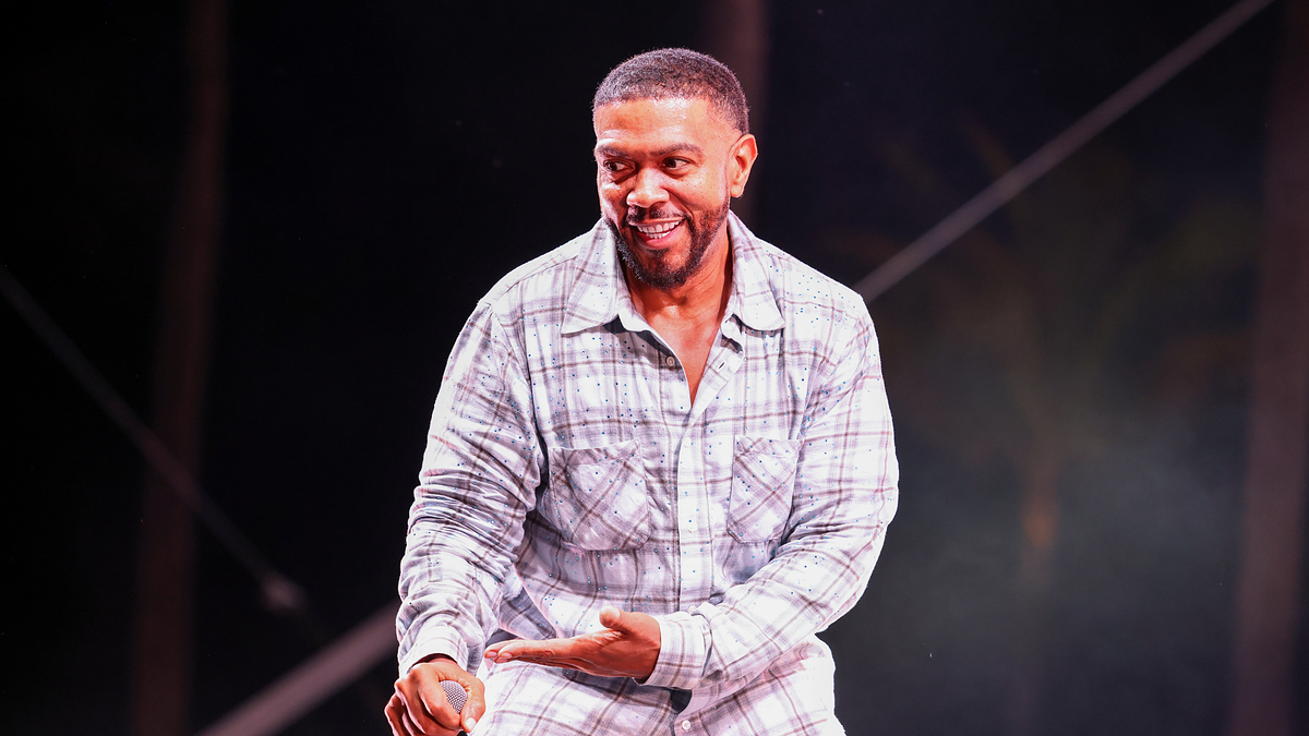 Timbaland performing on stage in a plaid shirt and camo pants