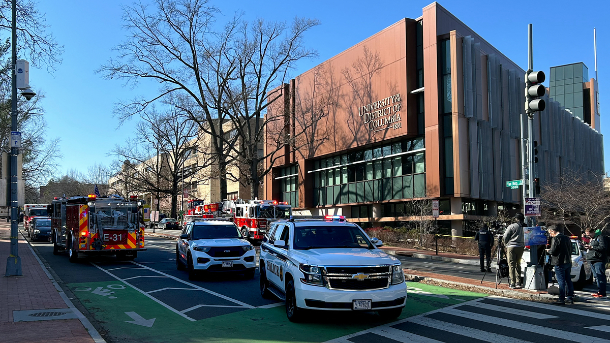 Emergency vehicles and bystanders outside a building on a city street