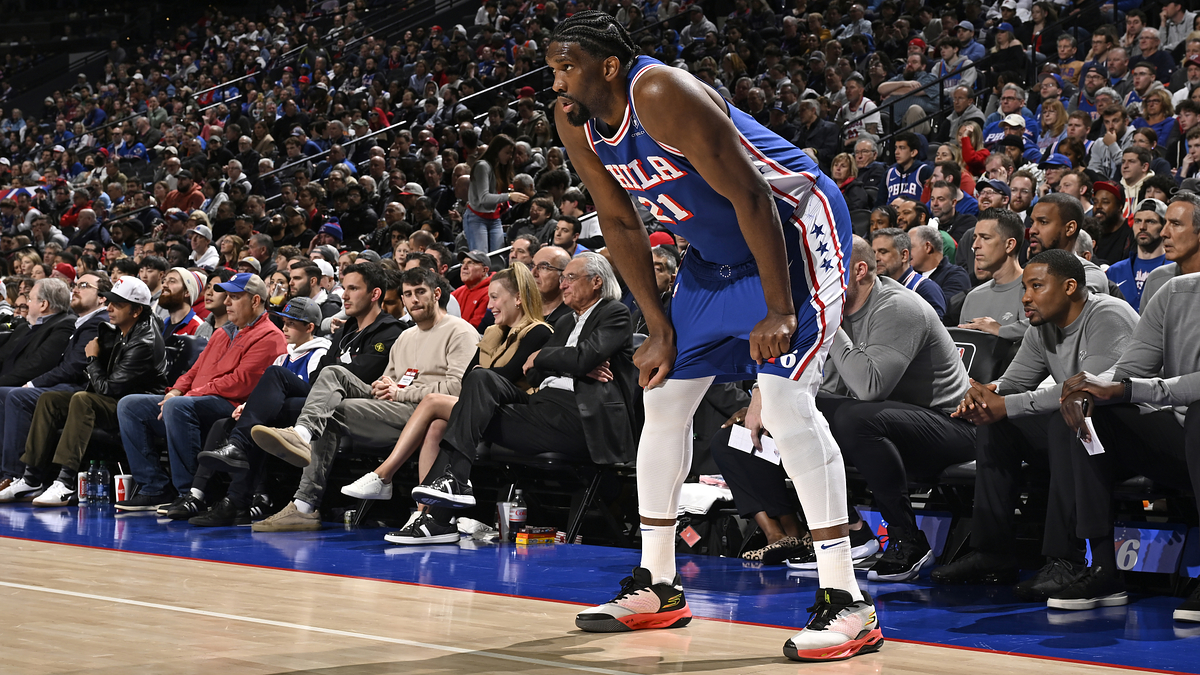 Basketball player on court in sneakers preparing to play, crowd in the background
