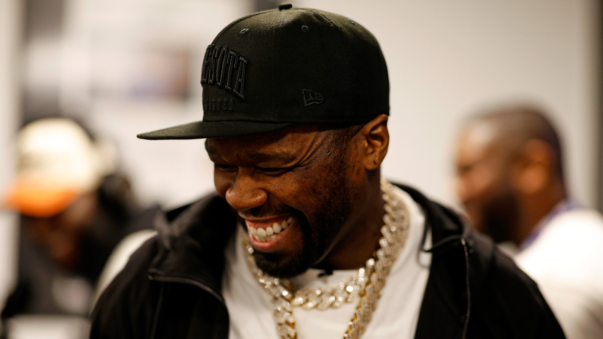 50 Cent in black cap and gold chain necklace laughing
