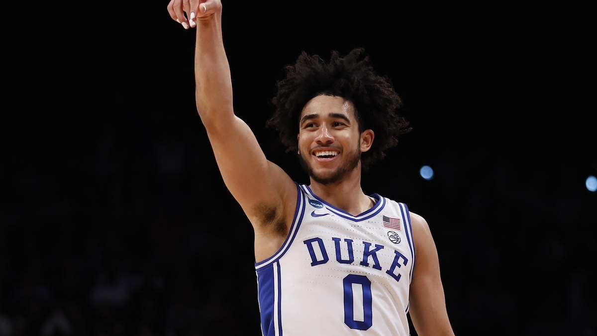 Basketball player in Duke jersey number 0 smiling and pointing upwards