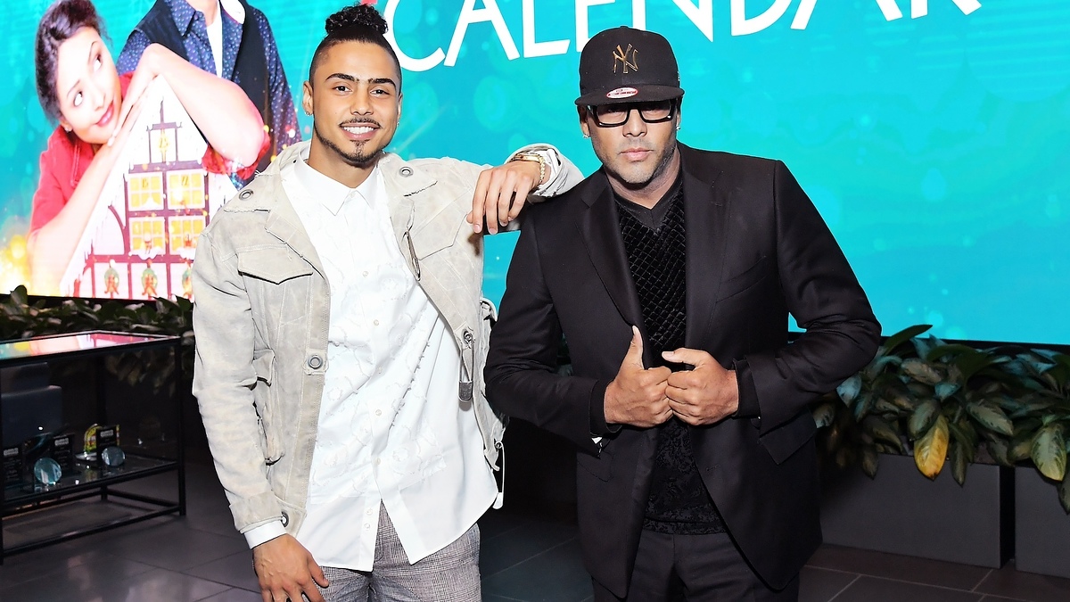 Two men posing for a photo at an event, one in a light jacket and the other in a black suit