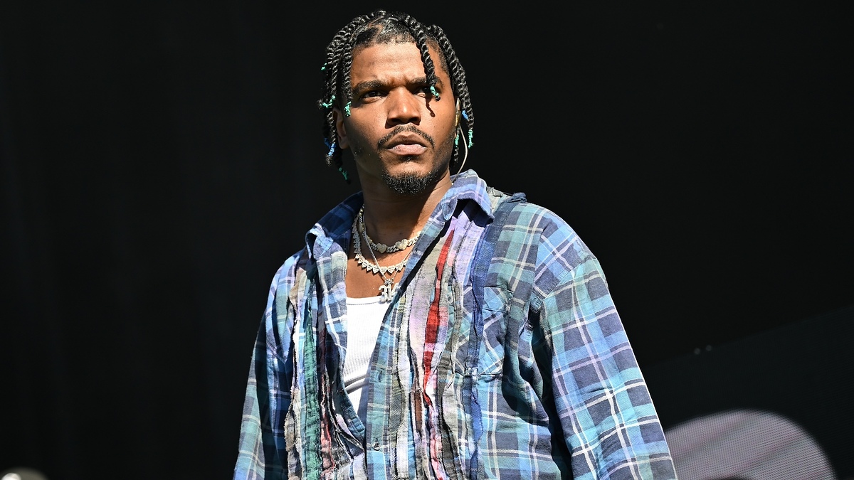 Travis Scott in a plaid jacket performs on stage