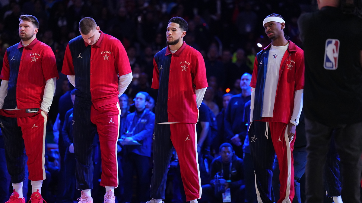 Four basketball players in red tracksuits standing on the court