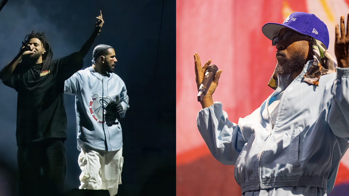 Two performers on stage, one with a raised peace sign and another with a microphone