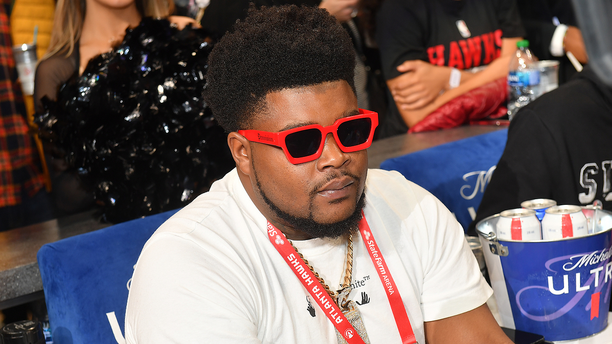 Person at an event wearing red sunglasses and a white t-shirt; appears focused