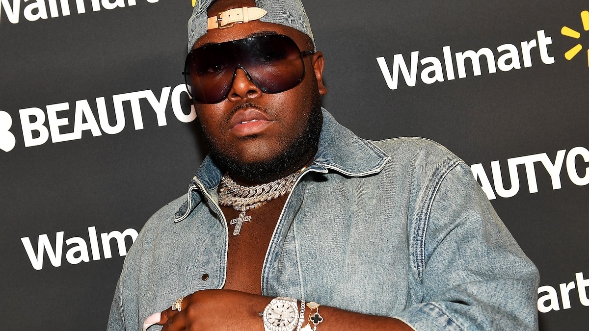 Man in denim outfit posing at Beautycon event, with event backdrop