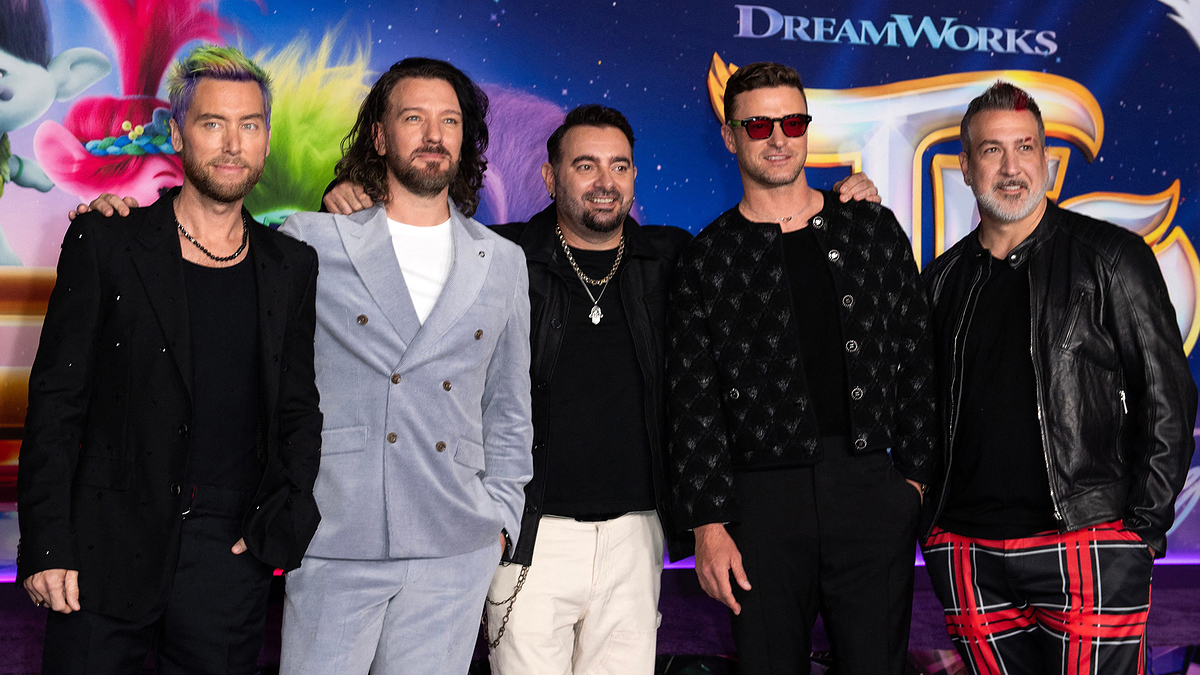 Five members of the NSYNC pose together at a DreamWorks event. They are dressed in various trendy outfits