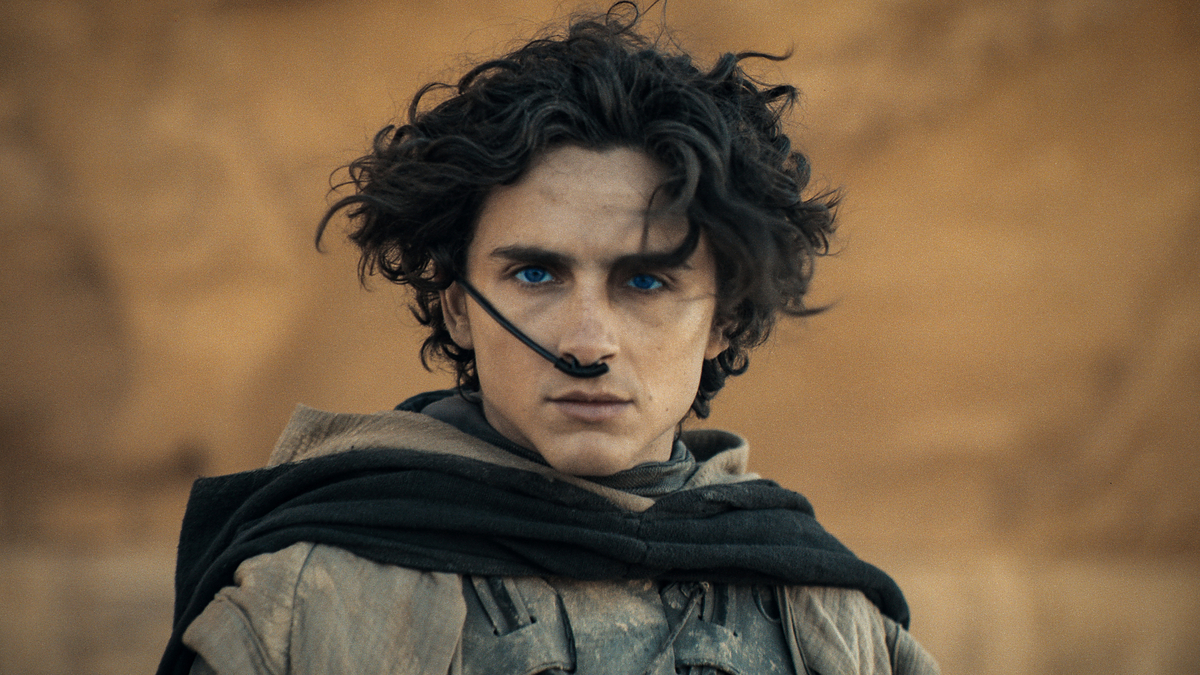 Person in character as Paul Atreides with a futuristic desert outfit and intense gaze