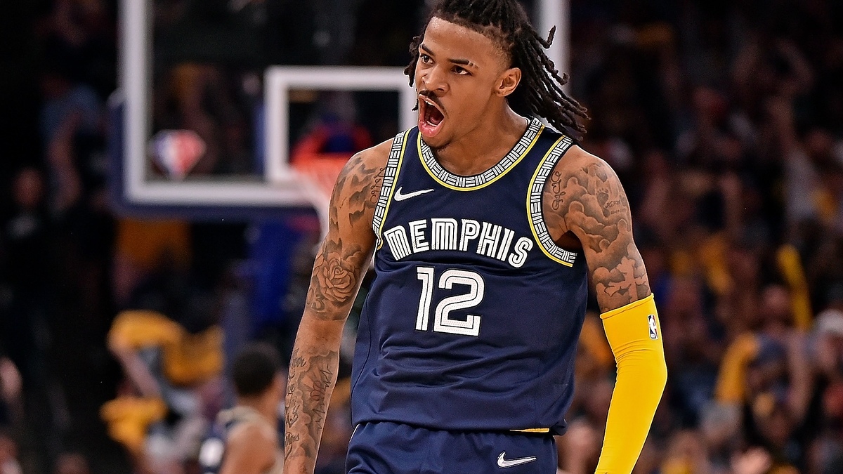 Basketball player in action on the court with "Memphis" jersey number 12, expressing excitement or shouting