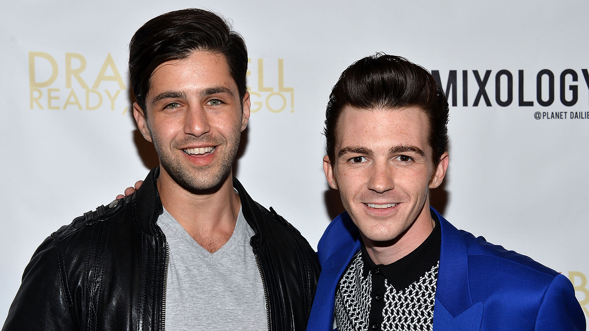 Two men smiling for a photo, one in a black leather jacket, the other in a blue blazer with a textured shirt