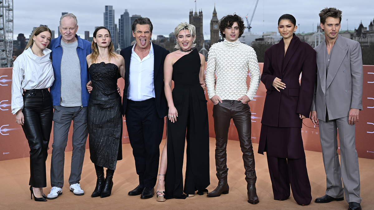 Cast of "Dune: Part Two" posing together; actors in stylish, varied formal wear on promotional event backdrop