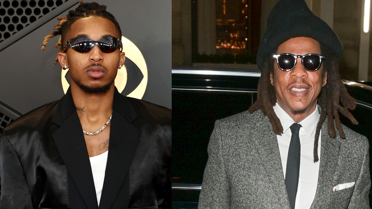 Two male musicians, one in a black tuxedo with a necklace, the other in a tweed jacket and hat, both wearing sunglasses