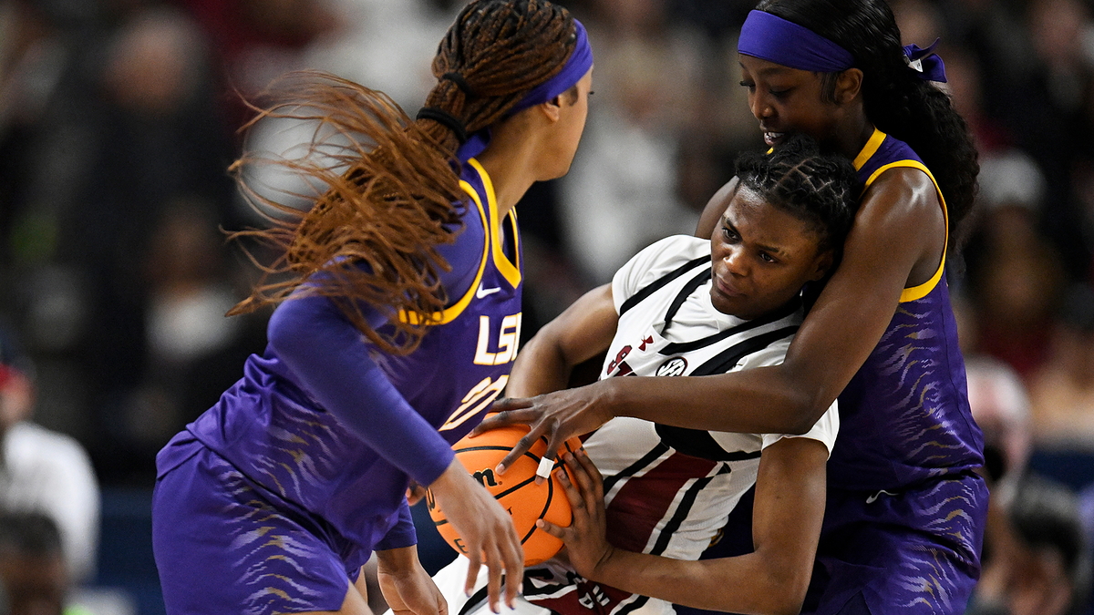 Three basketball players in action, one defending the ball against two opponents