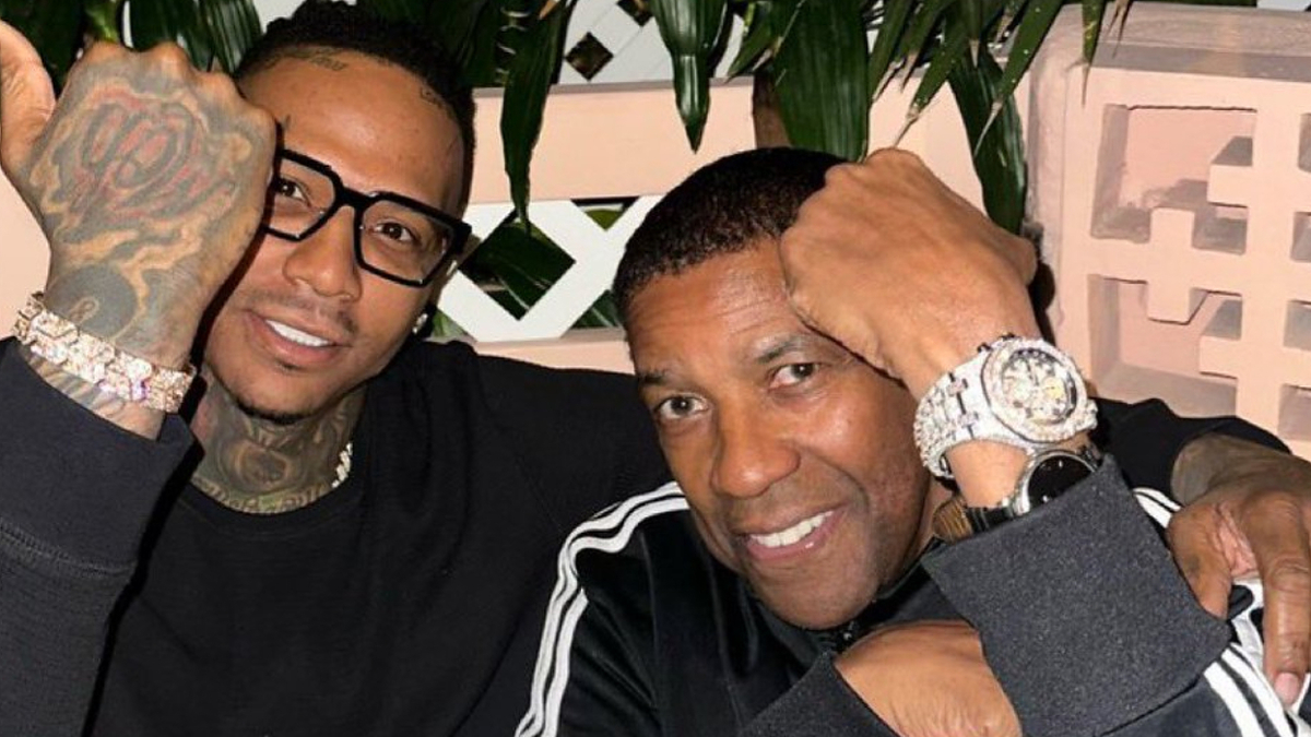 Two men posing for a photo, one with tattoos and a watch, the other smiling